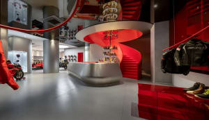 A lively modern bar with a red metal staircase, red walls, and a central bar with bottles