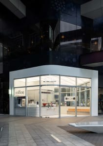 Bright and welcoming coffee shop with white interior, large window, appliances, and dining table