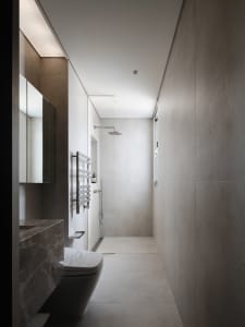 A modern bathroom with a white toilet and sink, a large mirror above the sink, and natural light from a window