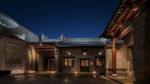 A large stone building with Chinese architectural style, adorned with intricate carvings, stands tall in a city street at night