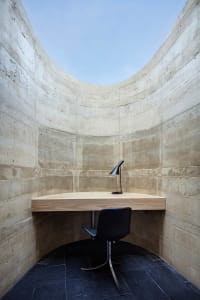 Small office space with a wooden desk and chair, wooden floor, and a window in the background