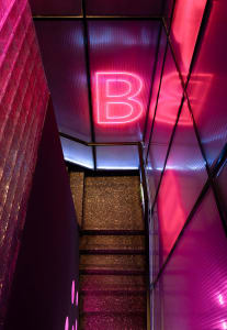A modern staircase in a hallway with a pink lighting effect, surrounded by a stylish interior setting