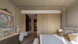 A modern bedroom with a wooden floor, a white bedspread, and a large window, with a bed positioned near the window and a dresser on the left side