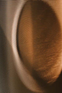 A close-up view of a dimly lit metal surface, possibly a speaker or wall, with a moody atmosphere and reflective texture