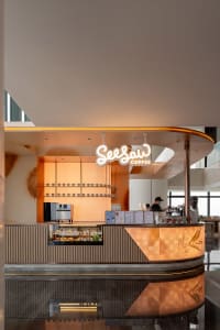 A modern coffee shop with a warm atmosphere, featuring a counter with a variety of food and drink options, surrounded by wood and metal elements, with soft and diffused lighting