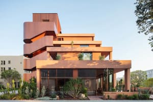 Modern building with a red brick exterior, curved structure, and large window, featuring a mix of residential and commercial spaces with natural light and a warm atmosphere