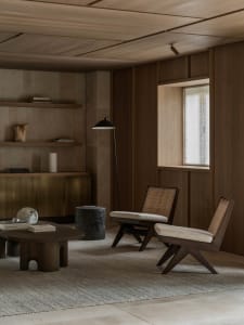 Cozy living space with wooden floors and walls, a couch, chair, and dining table, dim lighting, and a warm atmosphere