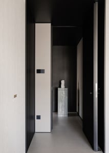 A dark and narrow hallway with wooden walls, a tile floor, and a statue on display, creating a simple and elegant atmosphere