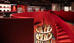 A cozy room with a spiral staircase, bar, and dining table, filled with bottles in various shapes and sizes, creating a visually appealing atmosphere