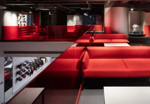 A modern living room with a red floor, glass walls, and a variety of furniture and decorative items