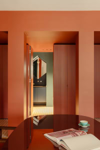 Warm and inviting kitchen with a red-painted wall, a glass dining table, and a wooden door leading to a hallway