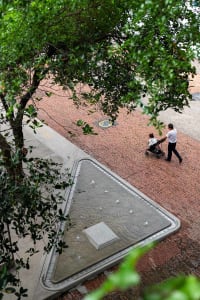 A man pushing a stroller on a brick sidewalk in an urban environment