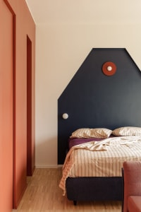 Cozy bedroom with a bed, chair, and red accent wall, suggesting a comfortable and inviting space