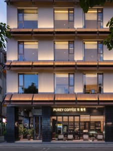 A welcoming coffee shop with a modern wooden building, large window, and natural lighting