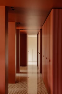 Warm and inviting hallway with red walls, tile floor, and lined with doors