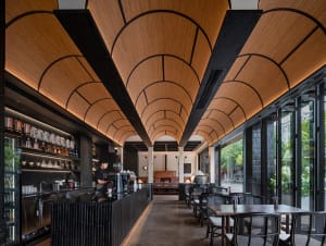 Cozy restaurant with dim lighting, wooden furniture, and metal accents, featuring a bar and dining area with potted plants and vases