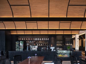 A well-lit restaurant with a wooden floor, a black counter, and a wooden table with chairs, set against a warm and inviting background