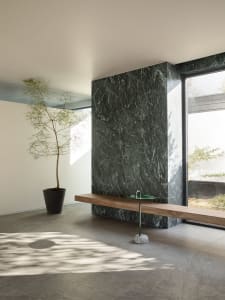 Cozy living space with a wooden bench near a window and a potted plant adding a touch of greenery