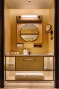 A cozy bathroom with a wooden sink, mirror, and nearby bed, creating a warm and inviting atmosphere