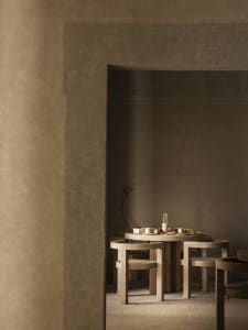 Dining room with a wooden table and chairs, surrounded by multiple bowls and cups, in a warm and inviting atmosphere with natural lighting