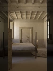 Cozy bedroom with a stone wall, wooden floor, a bed, and a chair near a window, dimly lit