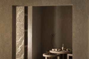 Cozy dining area with a stone table and chairs, surrounded by stone walls, with dim lighting and warm wood accents