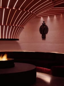 Cozy living room with a black couch, chair, and fireplace, illuminated by a fire