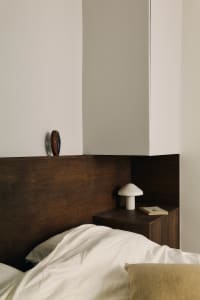 Cozy bedroom with a bed, cabinet, and nightstand, featuring predominantly wood materials and soft lighting