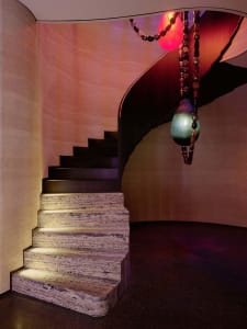 A stone staircase with a metal railing in a well-lit hallway, creating a warm and inviting atmosphere
