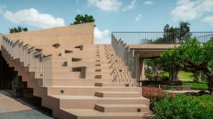 A stone staircase leads up to a concrete building wall, set against a natural background with a tree