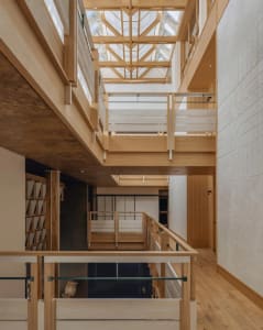 Open-plan living and dining space with wooden floors, a glass railing, and a dining table and chairs, well-lit and inviting