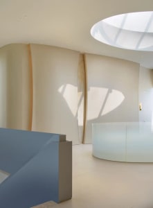 A bright and inviting modern room with a curved wall and glass wall, flooded with natural light