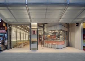 A modern restaurant with a large window, a bar, and dining tables, featuring a welcoming atmosphere and natural light
