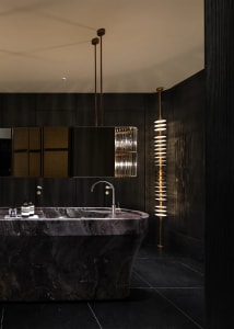 Bathroom with a metal sink, a marble basin, and a black and white color scheme, featuring dim lighting