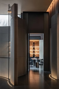 A well-lit dining space with a large window, a dining table, and a sink, featuring predominantly white materials and a sleek, contemporary style