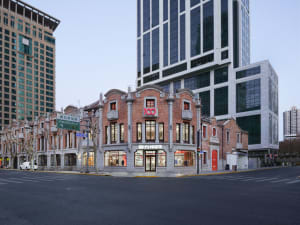 A large ornate building with a prominent red brick facade, clock tower, and arched entrance, set in a city environment with soft and diffused lighting