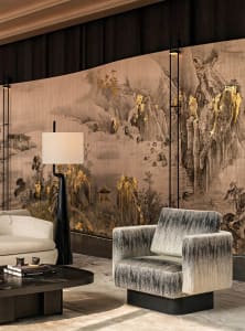 Comfortable living space with a gray couch, chair, and large wall mural, well-lit with natural and artificial light