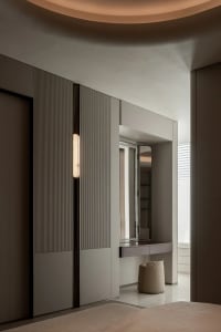 A dimly lit bathroom with grey walls, a large mirror, a sink, and a toilet
