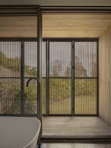 Bathroom with a bathtub and shower, surrounded by concrete walls and natural light from windows