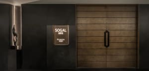 A dimly lit doorway with a traditional sign above it, set in a commercial or public space with a wooden doorway