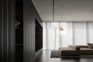 Dimly lit living room with a couch, chair, and lamp, suggesting a modern style with a focus on comfort and functionality