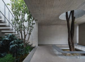 A photograph of a large concrete building with a circular design, surrounded by trees and natural scenery