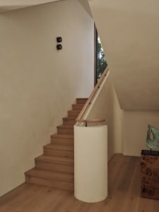 A wooden staircase with a white railing in a bright and welcoming hallway with a nearby window