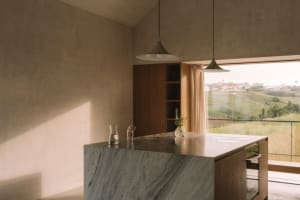 A well-lit kitchen with a marble countertop, sink, window, and door, designed for functionality and aesthetics