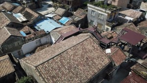 A city courtyard with a mix of old and new brick buildings, a staircase leading to a rooftop, and a charming atmosphere