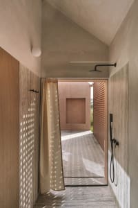 A cozy bathroom with a wooden floor and white walls, featuring a doorway leading to a patio with a view