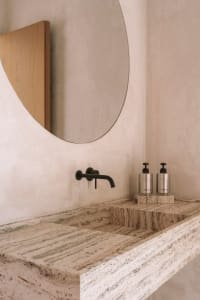 Bathroom with a marble sink and a large circular mirror, set in a clean and modern space with bright lighting