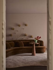 Cozy modern living room with a brown couch and chair, a vase with flowers on a table, and dim lighting