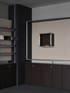 A clean and organized bathroom with a brown wooden cabinet and mirror, featuring various pairs of glasses arranged neatly on the cabinet