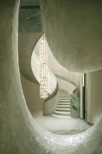 A dimly lit, curved marble staircase dominates the space, with no other objects or distractions visible